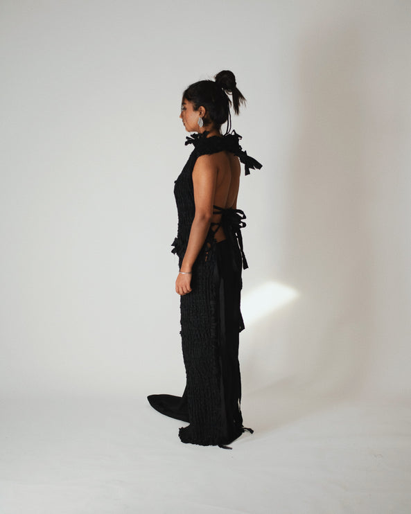 back of the model wearing a black woven dress